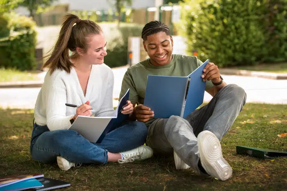 Amigos sentados con cuadernos dispuestos a estudiar ingles en el exterior