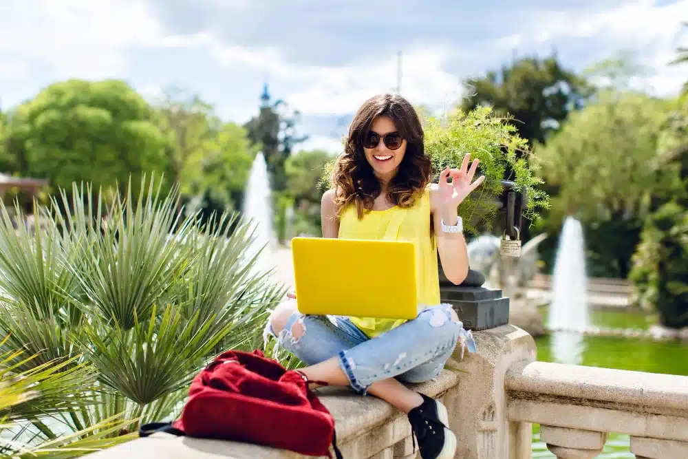Mujer con computador emocionada por el trabajo de medio tiempo mientras estudias en el exterior