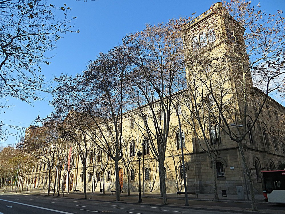 Fachada del Edificio Histórico de la Universidad de Barcelona entre plátanos, en la Gran Via